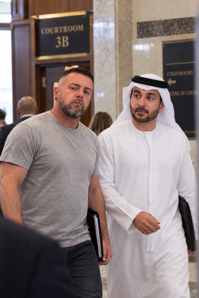 Two men walking past a Courtroom 3B sign in a courthouse hallway